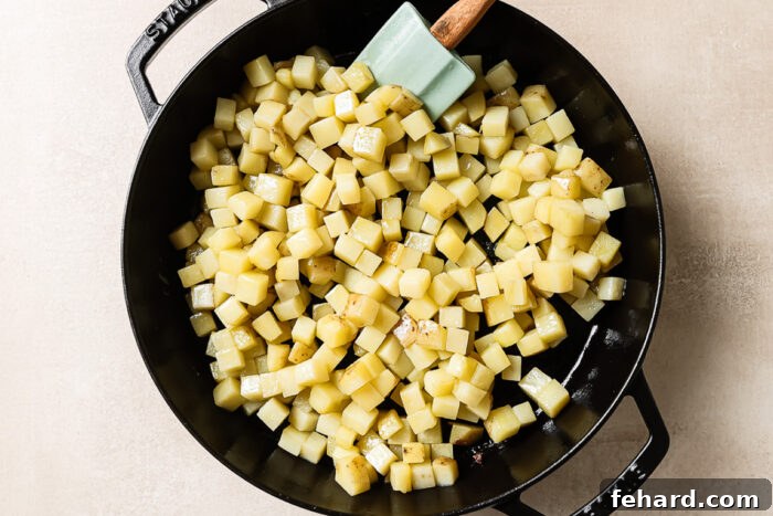 Overhead view of diced raw potatoes in a cast-iron skillet, ready for cooking.