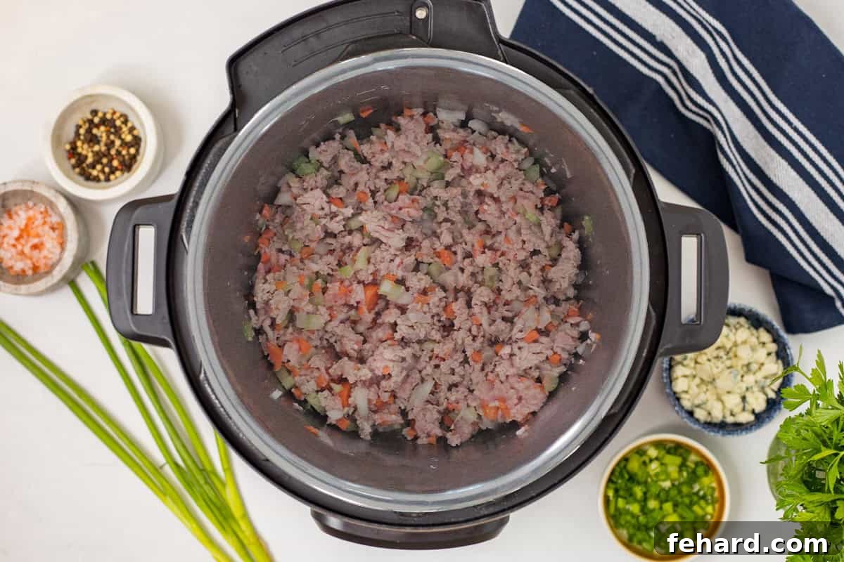 Ground chicken sauteed with onions, carrots, and celery inside instant pot.